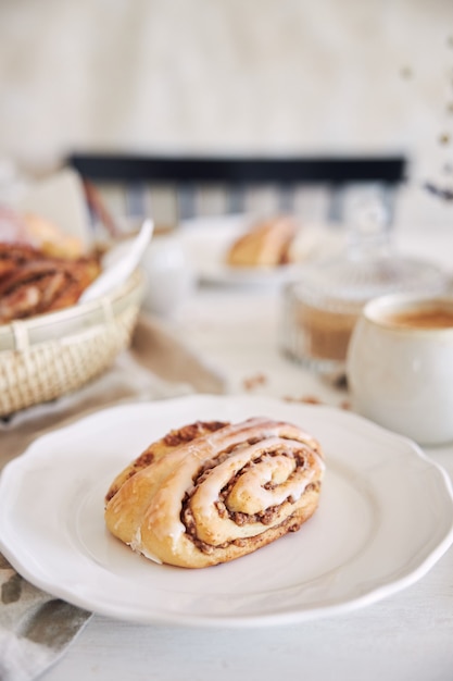 Free photo vertical closeup shot of delicious nut snails with coffee cappuccino on the white wood table