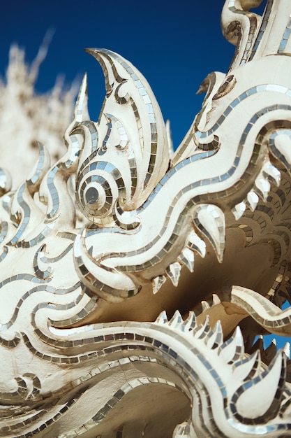 Vertical closeup shot of a dragon statue in the White Temple in Chiang Rai, Thailand