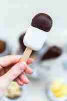 Free photo vertical closeup shot of a female hand holding a raw vegan ice-cream on stick