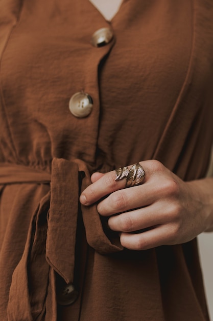 Free photo vertical closeup shot of a female wearing a brown dress and a metallic leaf-shaped ring