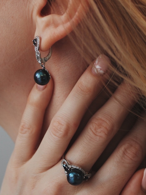 Free photo vertical closeup shot of a female wearing a ring and earrings with a black pendant