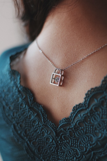 Free photo vertical closeup shot of a female wearing a silver necklace with a beautiful lock pendant