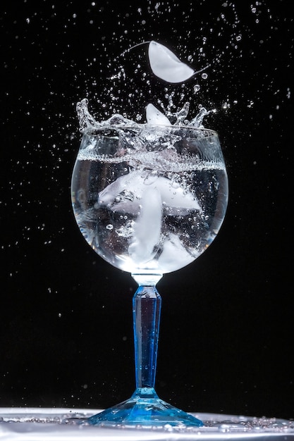 Vertical closeup shot of a glass of iced water with splashes