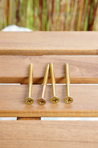 Vertical closeup shot of golden cross screws on a golden table