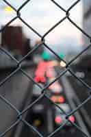 Free photo vertical closeup shot of gray chain link fence on a blurry background of street