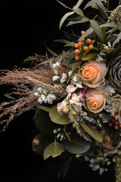 Free photo vertical closeup shot of a luxurious bouquet of orange and brown roses on a black background