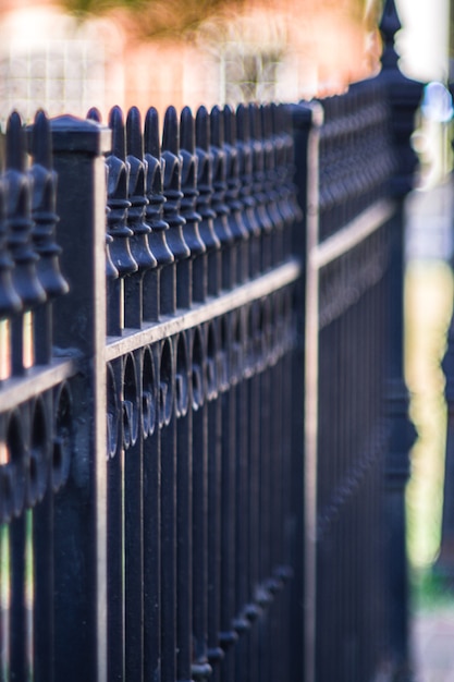 Vertical closeup shot of a metal fence on a sidewalk