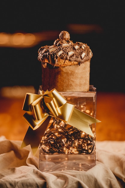 Free photo vertical closeup shot of a romantic box with lights, a gold ribbon, and a muffin