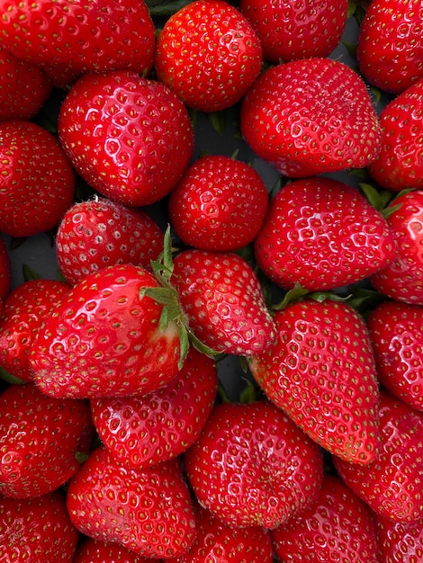 Free photo vertical closeup shot of vibrant red juicy fresh strawberries