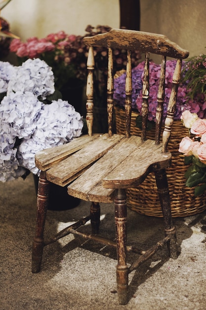 Free Photo vertical closeup shot of a vintage wooden chair surrounded by baskets with flowers