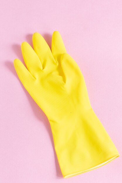 Vertical closeup shot of a yellow plastic glove on a pink surface