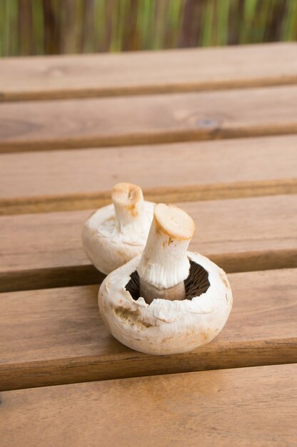 Vertical closeup of two fresh mushrooms on a wooden table surface