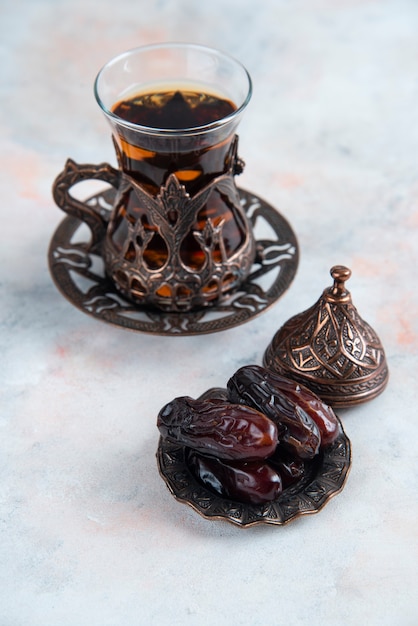 Vertical of dry dates and fresh tea on grey surface