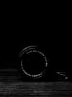 Free photo vertical gray scale shot of a camera lens on a wooden surface