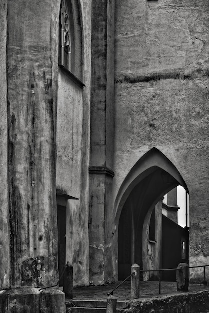 Free Photo vertical grayscale shot of an old stone historical building with an arch-shaped door