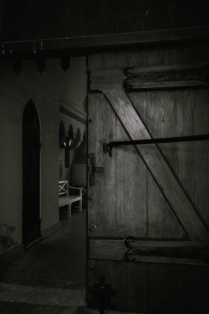 Free photo vertical grayscale shot of an old wooden door inside a historical building