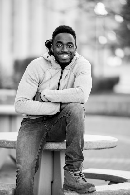 Vertical greyscale shot of an attractive African American male smiling at the camera