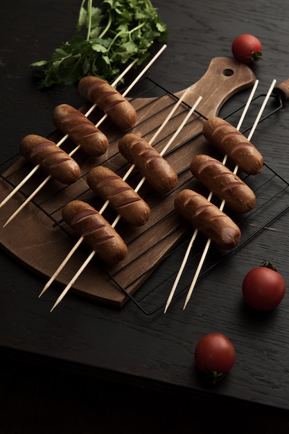 Vertical high angle shoot of barbequed sausages and cherry tomatoes on a wooden surface