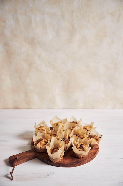 Free photo vertical high angle shot of delicious chocolate muffin on a wooden plate on a white table