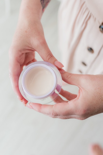 Vertical high angle shot of a female in a pink dress holding a small cup of milk