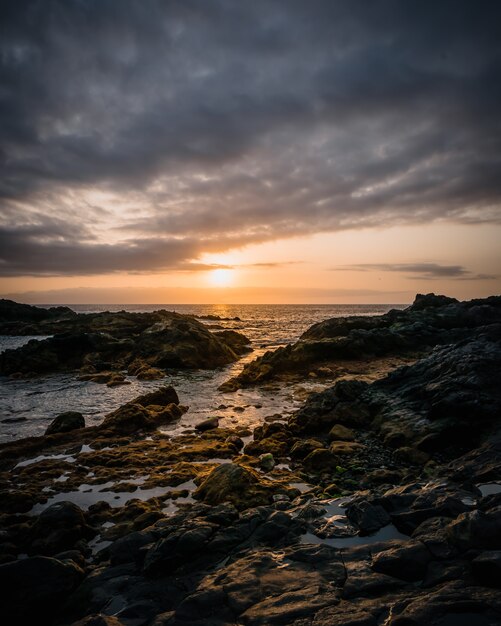 Vertical high angle shot fo the rock formations n the shore of the sea under the cloudy sky