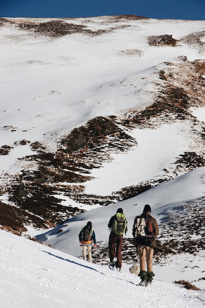 Free Photo vertical high angle shot of hikers with backpacks in the snowy mountains