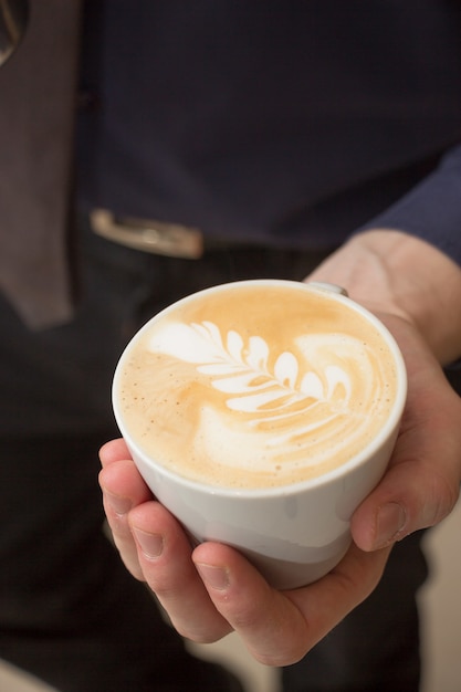 Vertical high angle shot of a man holding a cup of cappuccino