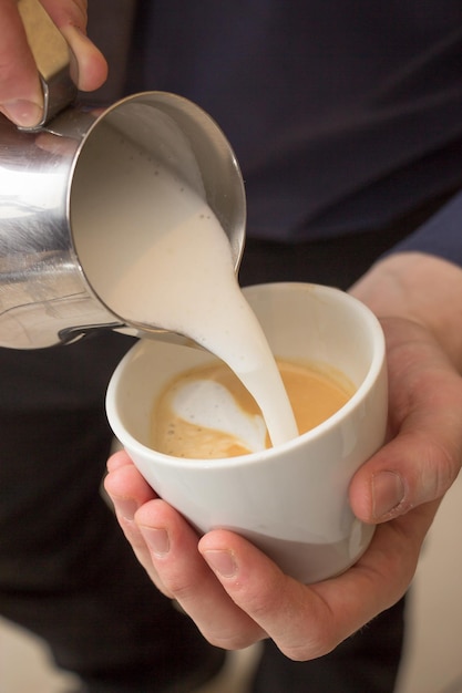 Vertical high angle shot of a man making a cup of cappuccino