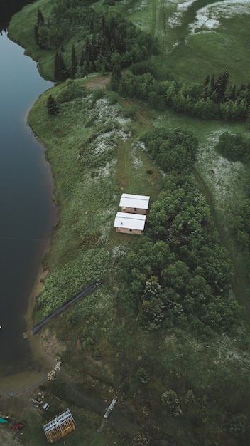 Free Photo vertical high angle shot of two cottages on the edge of a tropical jungle over a river