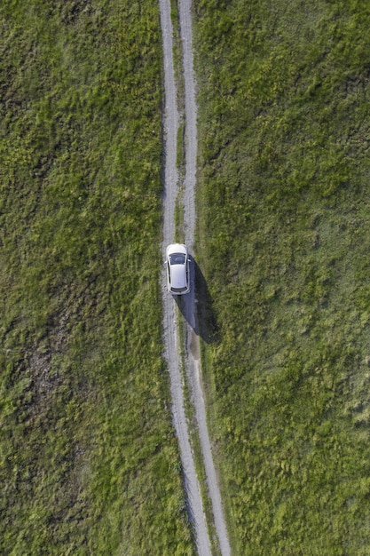 Free photo vertical high angle shot of a white car riding through the path in the green valley