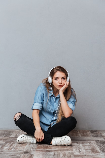 Vertical image of Woman listening to music on the floor