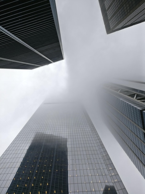 Free photo vertical low angle shot of a tower block enveloped in fog