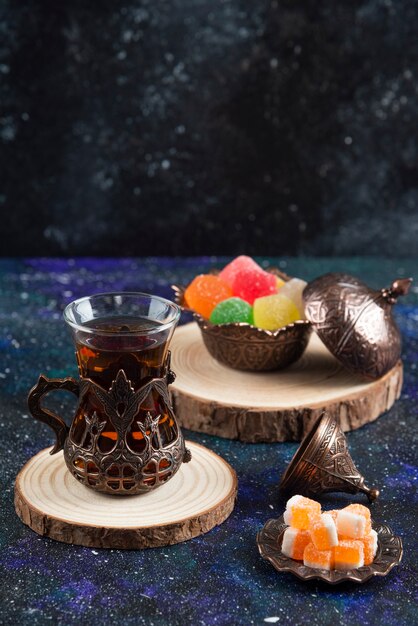 Vertical photo of colorful candies and fragrant tea on blue surface