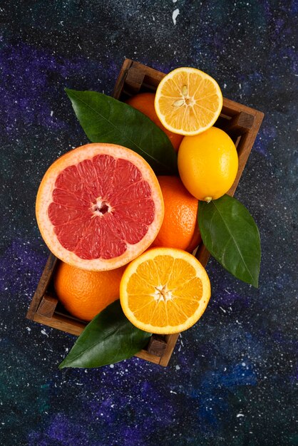 Vertical photo of fresh citrus fruits in wooden basket.