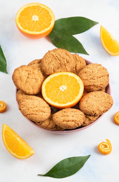 Vertical photo of homemade cookies with half cut orange in bowl.