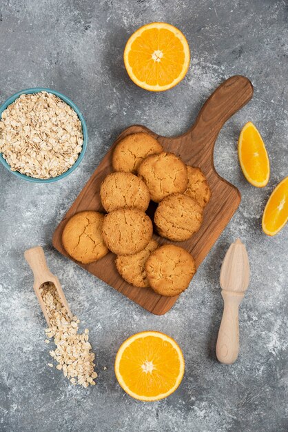 Vertical photo of homemade cookies with oatmeal and orange slices over grey table.