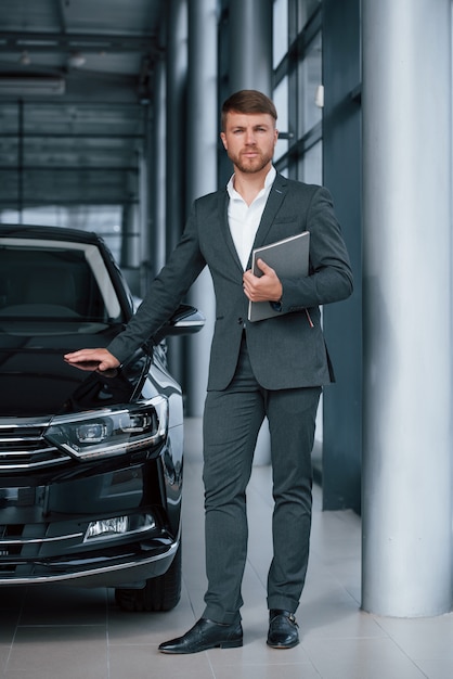 Vertical photo. Modern stylish bearded businessman in the automobile saloon