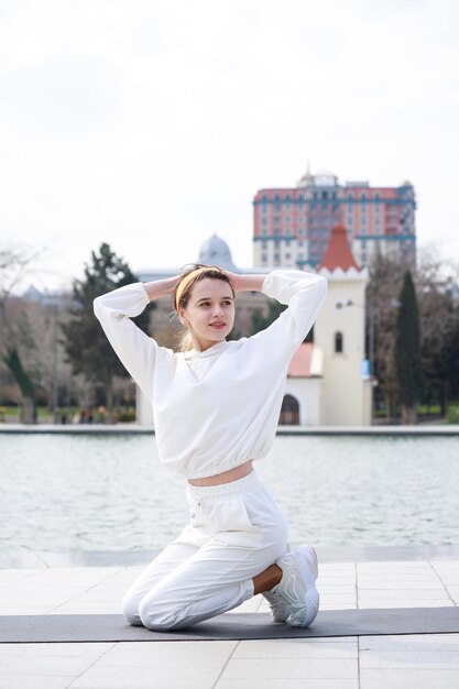 Vertical photo of young athlete sitting on yoga mat and put her hands behind of her back High quality photo