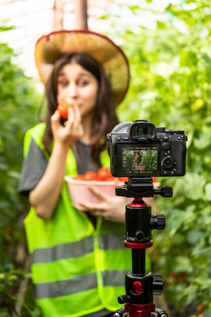 Vertical photo of young beautiful lady in front of a camera at the greenhouse