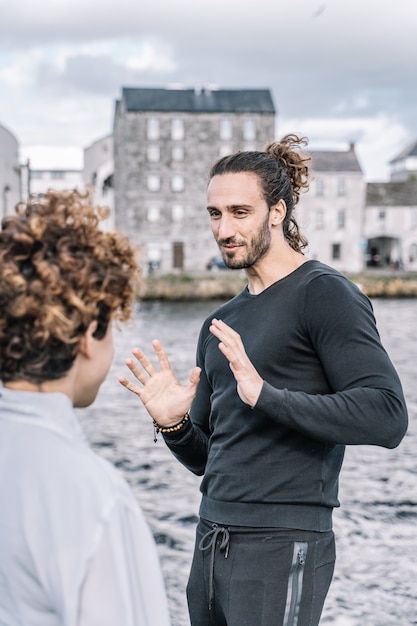 Vertical photo of a young couple arguing expressively with the unfocused  sea