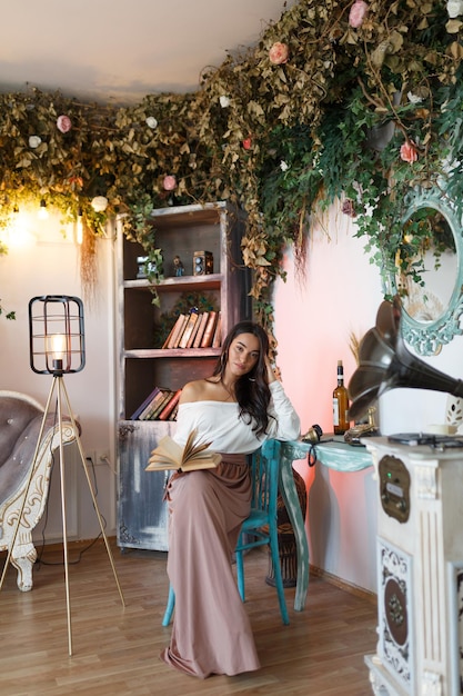 Free photo vertical photo of young girl sitting on a chair and reading book high quality photo