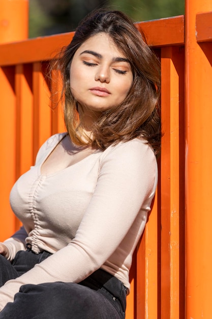 Vertical photo of young lady sittin on the ground and leaning on the wall High quality photo