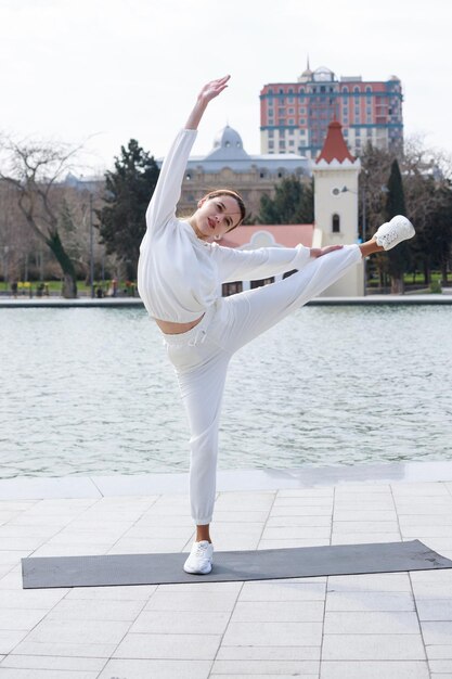 Vertical photo of young lady stretching her legs at the park High quality photo