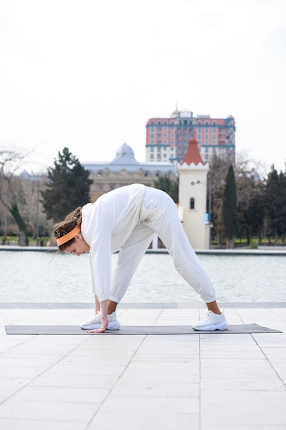 Vertical photo of young lady stretching herself at the park Outdoor exercises High quality photo