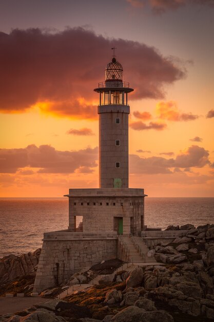 Vertical picture of the Punta Nariga lighthouse surrounded by the sea during the sunset in Spain