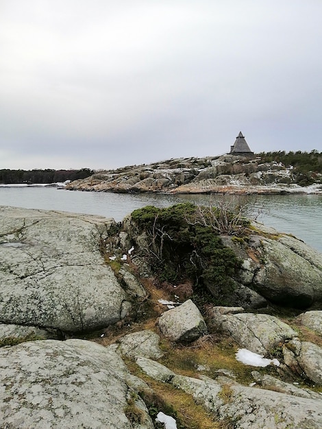 Vertical picture of rocks surrounded by the river under a cloudy sky in Norway