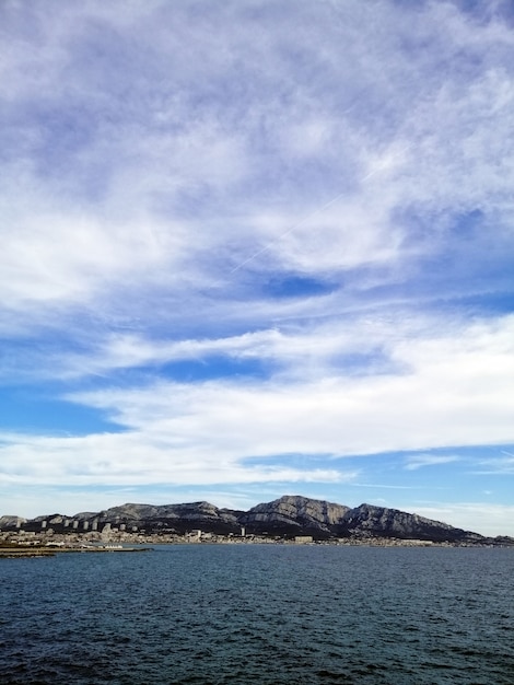 Vertical picture of the sea surrounded by rocks under a cloudy sky in Marseille in France