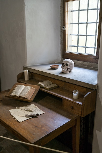 Vertical of a poet's room with a skull, papers and a book on the work desk