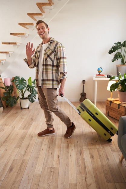 Free photo vertical portrait of happy friendly man guy waves hand at camera and says hello or bye goes on