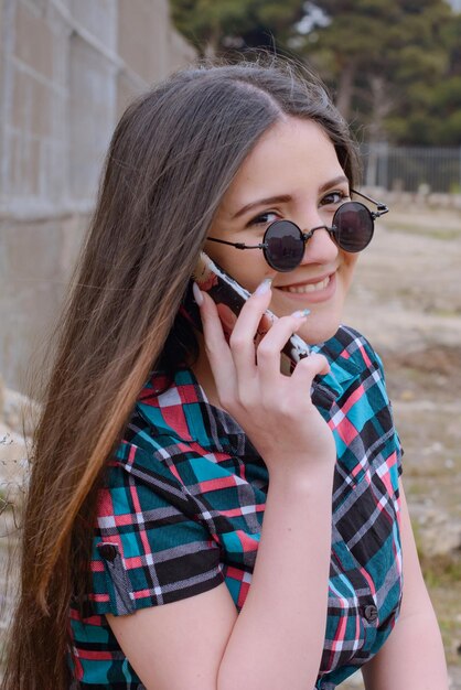 Vertical portrait of smiling youn girl talking on the phone